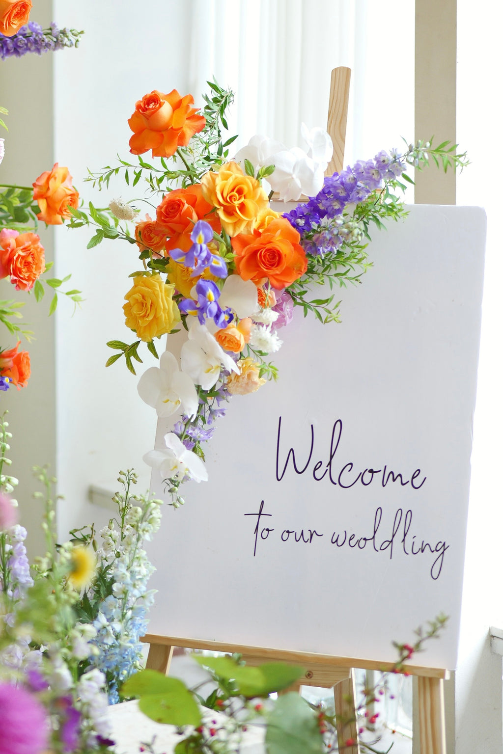 Floral arrangement with a Welcome sign on an easel.