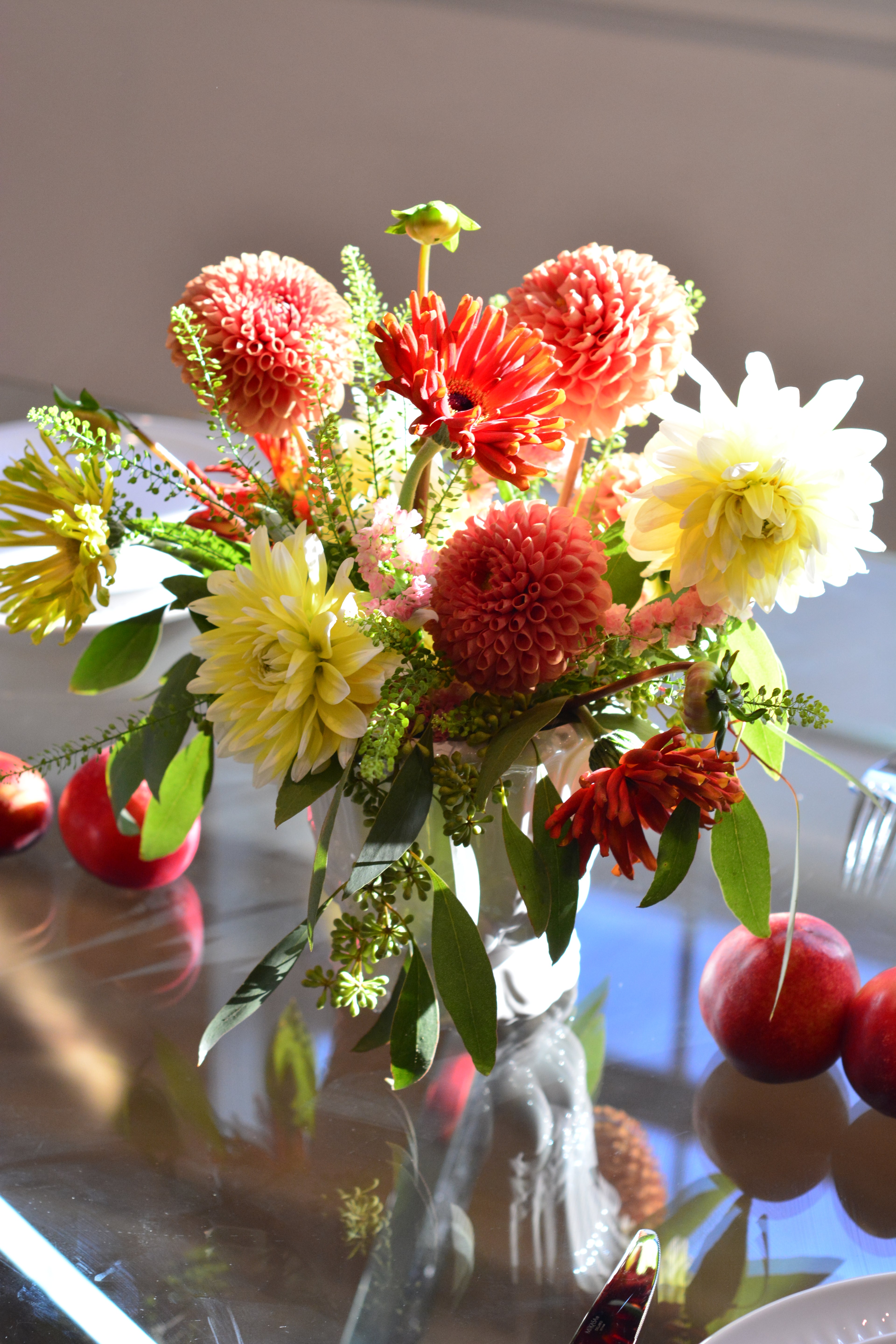 Classic garden centerpiece featuring dahlias, gerbera daisies, chrysanthemums, astilbe, seasonal blooms, and greenery arranged in a white vase.