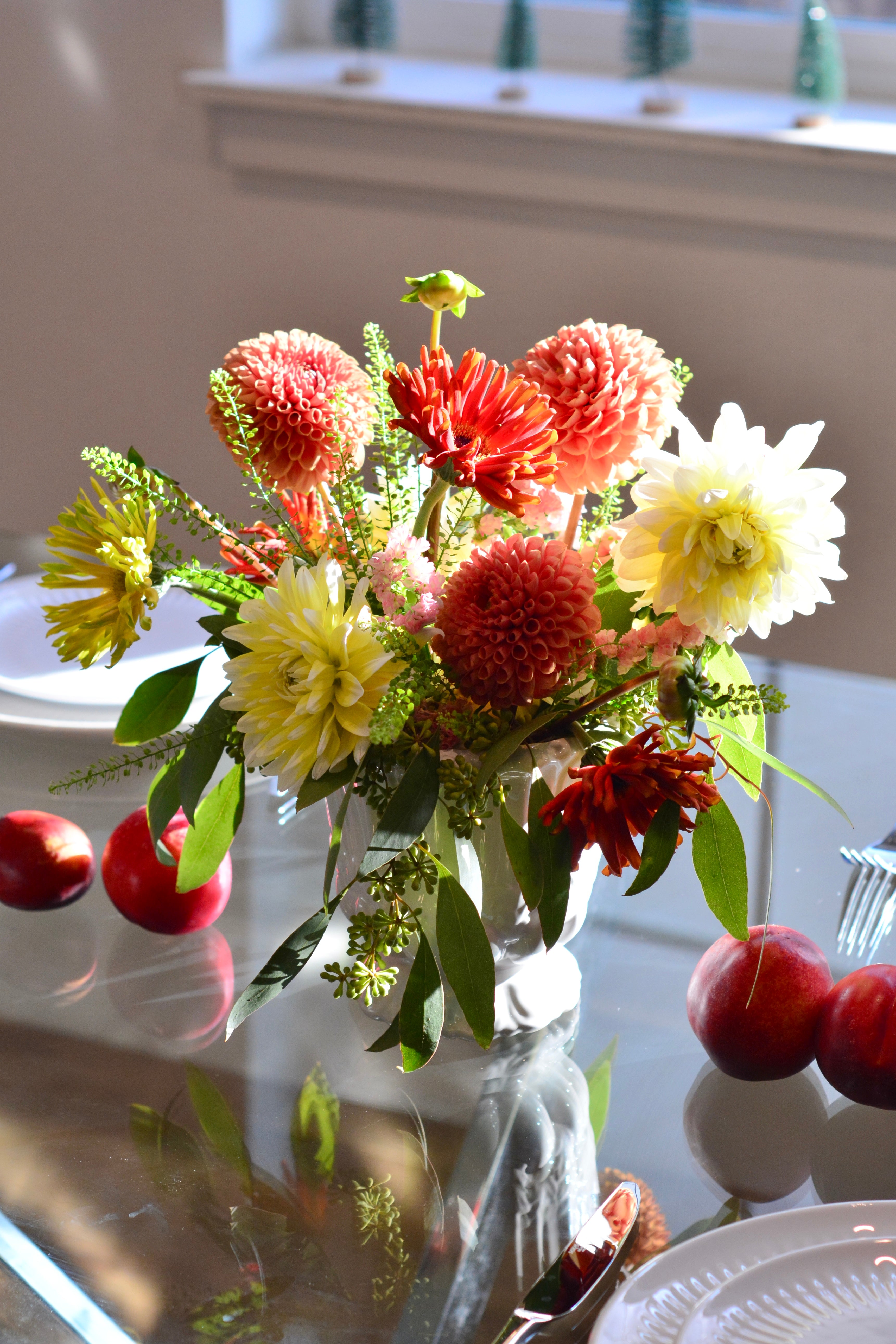 Classic garden centerpiece featuring dahlias, gerbera daisies, chrysanthemums, astilbe, seasonal blooms, and greenery arranged in a white vase.
